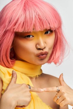 Pembe saçlı hayat dolu genç kadın sarı renkler içinde neşeli ruhunu sergiliyor..