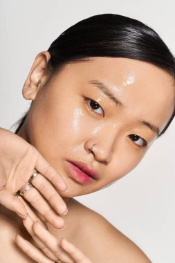 Zarif genç Asyalı kadın zarif poz verirken doğal güzelliği parlak cildiyle kucaklıyor..