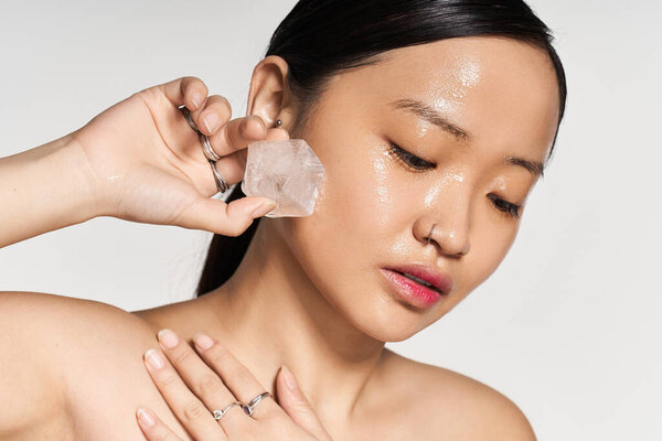 Красивая молодая азиатка использует кристалл для своей кожи, подчеркивая сияющую и здоровую кожу.