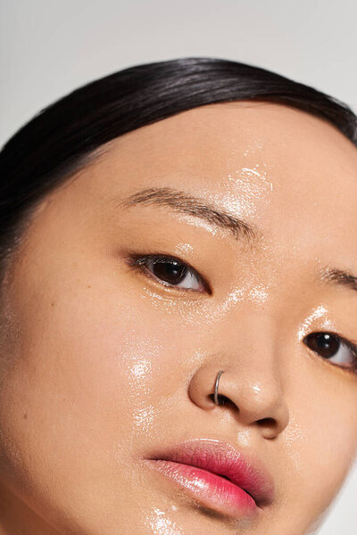 Азиатская женщина подчеркивает свою сияющую кожу, обнимая естественную красоту в успокаивающей обстановке.