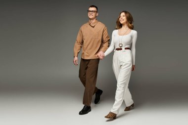 Gelin ve damat el ele yürür, zarif elbiseleriyle sevgi ve neşe saçar.