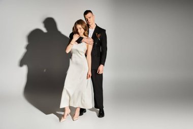 Beyaz elbiseli gelin ve siyah takım elbiseli damat aşkı şık ve romantik bir pozla kutluyorlar..