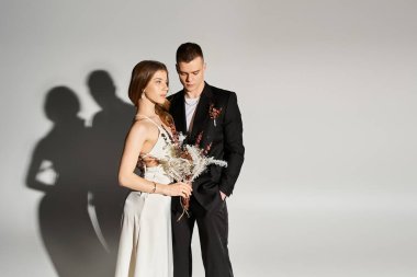 Genç gelin ve damat, zarif kıyafetlerini ve sevgilerini sergilerken romantik bir anı paylaşıyorlar..