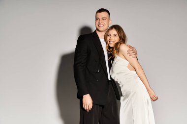 Güzel bir gelin ve damat, şık elbiseleriyle mutluluk saçan sevgi dolu bir kucaklaşmayı paylaşıyor..