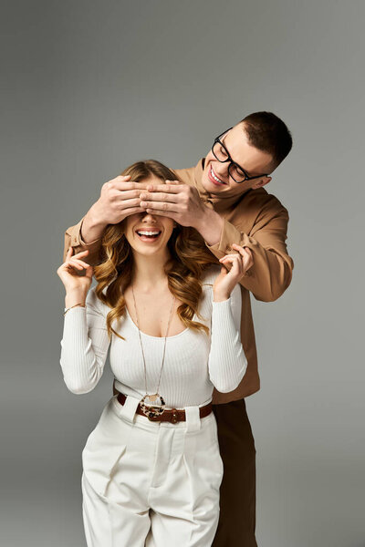 A playful groom covers his brides eyes, capturing a joyful moment of love.