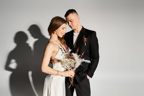 Young bride and groom share a romantic moment against a soft, neutral backdrop.