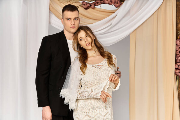 A stunning bride and groom share a heartfelt embrace under flowing drapes, radiating love.