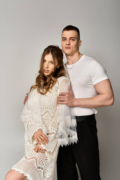 Красивая невеста в кружевном платье обнимает своего красивого жениха, излучая вместе любовь и элегантность.