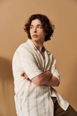 Yakışıklı bir genç, bir stüdyoda düşünceli bir şekilde dururken şık bir yaz kıyafeti sergiliyor..