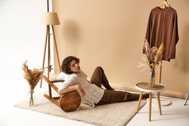 Yakışıklı bir genç adam şık bir yaz elbisesi içinde etrafı dekorla çevrili olarak rahatça uzanır..