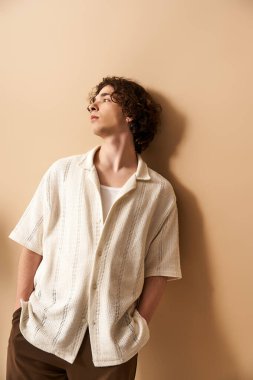 Kıvırcık saçlı yakışıklı bir genç poz verirken şık bir yaz kıyafetine güvenir..