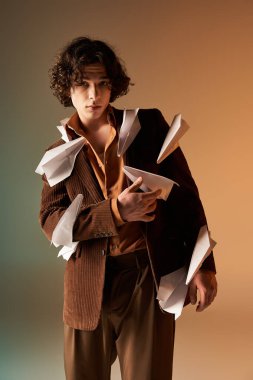 Kahverengi kadife ceket giymiş yakışıklı bir genç stüdyoda yaratıcı bir şekilde poz veriyor..