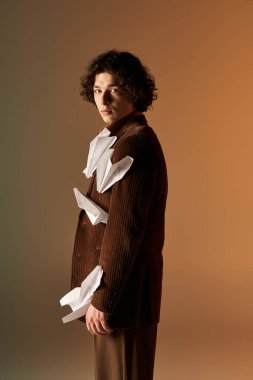 Kıvırcık saçlı, kendine güvenen genç bir adam uçakları olan eşsiz kahverengi bir kadife ceket giyer..