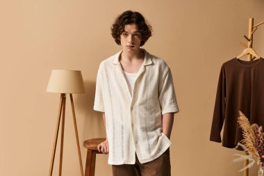 Kıvırcık saçlı yakışıklı bir genç stüdyoda şık bir yaz kıyafeti sergiliyor..