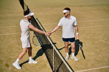 Güneşli bir günde yoğun bir tenis maçından sonra iki yetenekli adam ağda el sıkışıyor..
