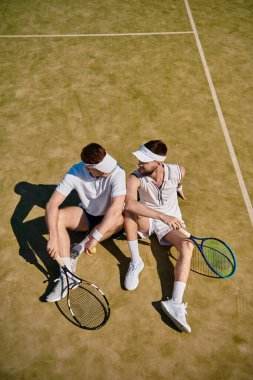 İki genç adam güneşli bir yaz gününde tenis oynadıktan sonra eğlenceli bir anın tadını çıkarırlar..