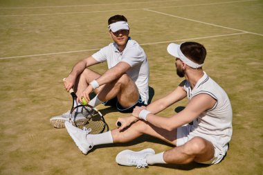 İki adam rahatlar ve tenis kortunda sohbet ederler. Yaz sporlarında birlikte vakit geçirirler..