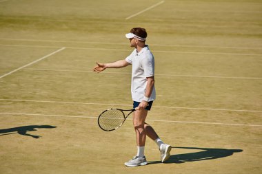 Yetenekli bir oyuncu, iyi bakılmış bir kortta tenis oynarken yaz gününün tadını çıkarıyor.