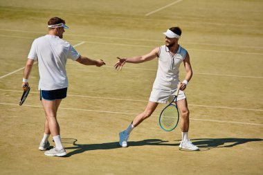 Ilık bir yaz gününde iki çekici erkek, yeteneklerini sergileyerek canlı bir tenis maçından zevk alırlar..