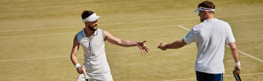 Yakışıklı oyuncular heyecan verici bir tenis maçına katılıyorlar. Yaz günü gülümsüyorlar ve yarışıyorlar.