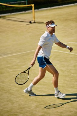 Beyaz spor giyimli yetenekli bir oyuncu yaz boyunca tenis kortunda yeteneğini sergiliyor..