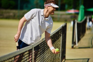 Yetenekli bir oyuncu, canlı bir yaz gününde tenis kortunda hizmet etmeye hazırlanıyor..
