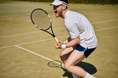 Dinamik sporcu, parlak bir yaz gününde tenis oynarken bir puan kazandıktan sonra sevinç ifade eder..