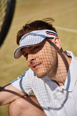 Beyaz giyimli bir adam, güneşli bir yaz gününde tenis oynarken yeteneklerini sergiliyor..
