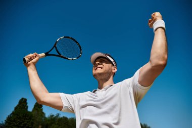 Yetenekli bir oyuncu, güzel güneşli bir günde tenis kortunda başarılı bir atışı kutlar..