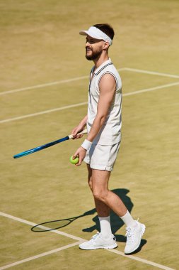 Yetenekli bir oyuncu, canlı bir kortta beyaz giysiler içinde tenis oynarken güneşli bir günün tadını çıkarır..