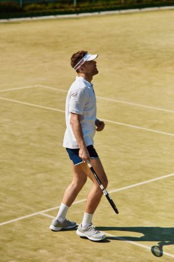 Formda bir adam yaz güneşinin altında tenis oynar, enerjisini gösterir ve sahaya odaklanır..