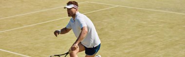 Beyaz takım elbiseli yakışıklı bir adam parlak bir yaz gününde tenis yeteneklerini sergiliyor.