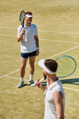 İki adam yaz güneşinin altında heyecan verici bir tenis maçı yapıyorlar, neşe ve dostluk saçıyorlar..