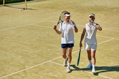 Yakışıklı erkekler yaz güneşinde tenis maçına ara verip susuz kalmazlar..