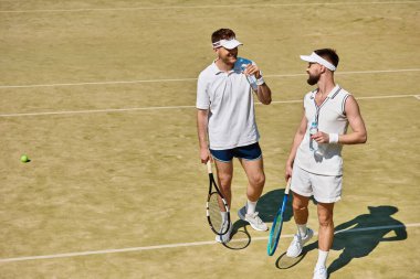 İki genç adam yaz güneşinin altında dostça bir tenis maçının tadını çıkarıyor..