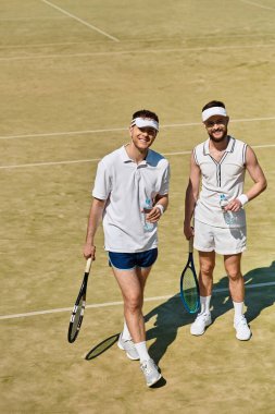 Yakışıklı erkekler tenis kortunda keyifli bir anı paylaşıyorlar, açık havada yapılacak dostça bir maça hazırlanıyorlar..