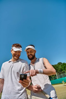 İki adam tenis oynuyor, kortta keyifli anlar yaşıyorlar..