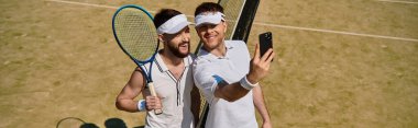 Tenis kortunda en sevdikleri spor olan pankartı oynarken iki adam neşeli bir anı paylaşıyor.