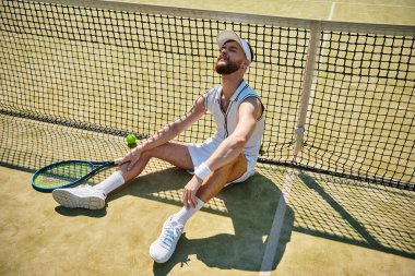 Yetenekli bir oyuncu, güneşli bir yaz günü sahada yoğun bir tenis maçından sonra dinlenir..