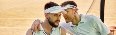 Güneşli bir kortta tenis oynadıktan sonra iki genç aynı neşeli anı paylaşıyor.