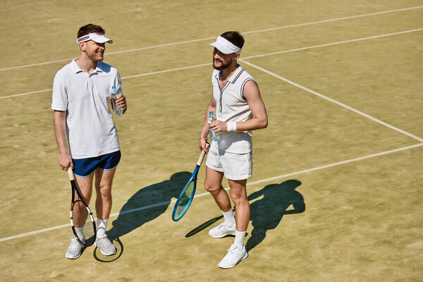 Двое мужчин играют в теннис в теплый летний день, улыбаются и делятся радостными моментами вместе.