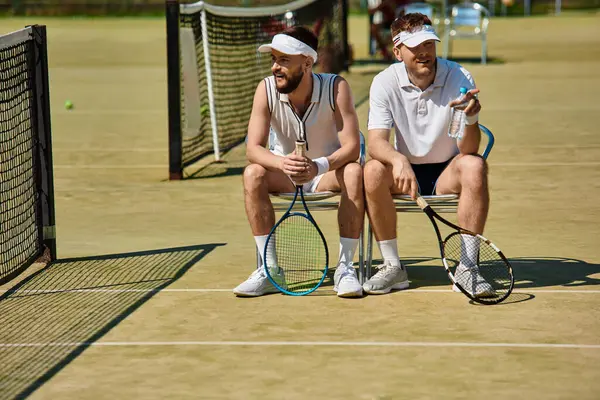Yaz güneşinde heyecanlı bir tenis maçından sonra iki arkadaş koltuklarda rahatlar, maçın tadını çıkarırlar..