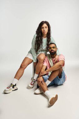 Şık bir çift, kendine güvenerek poz verir. Parlak bir stüdyo ortamında aşkı ve stili ifade eder..