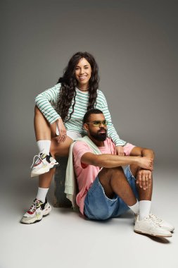 Bir çift, modern romantizmi yakalamak için şık bir stüdyoda birlikte poz vererek güven ve tarz yayıyor..