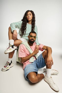 Çift şık bir şekilde stüdyoda poz veriyor, modaya uygun kıyafetler giyip romantik bir hava katıyor..