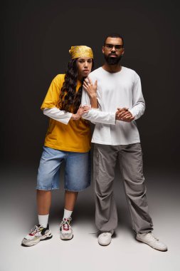 Şık bir çift yaratıcı bir stüdyoda poz veriyor, benzersiz moda ve bağlantılarını vurguluyor..