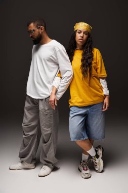 Bir çift modern stüdyo ortamında poz verirken eşsiz moda tercihlerini sergiliyor..