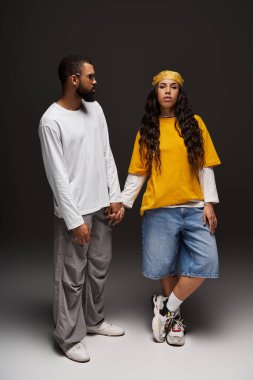 Bir çift el ele durur, şık moda anlayışlarını ve derin bağlantılarını ifade ederler..