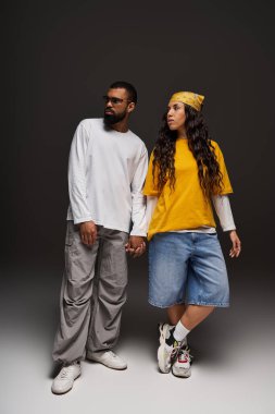 Bir çift el ele durur, karanlık bir arkaplana karşı bir tarz ve bağlantı yayarlar..