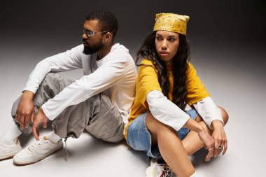 Şık bir çift sırt sırta oturur, modaya uygun kıyafetlerle aşklarını sergilerler..